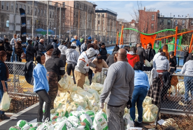 This image shows a group of people participating in the Chopra & Nocerino turkey giveaway service in Brooklyn.
