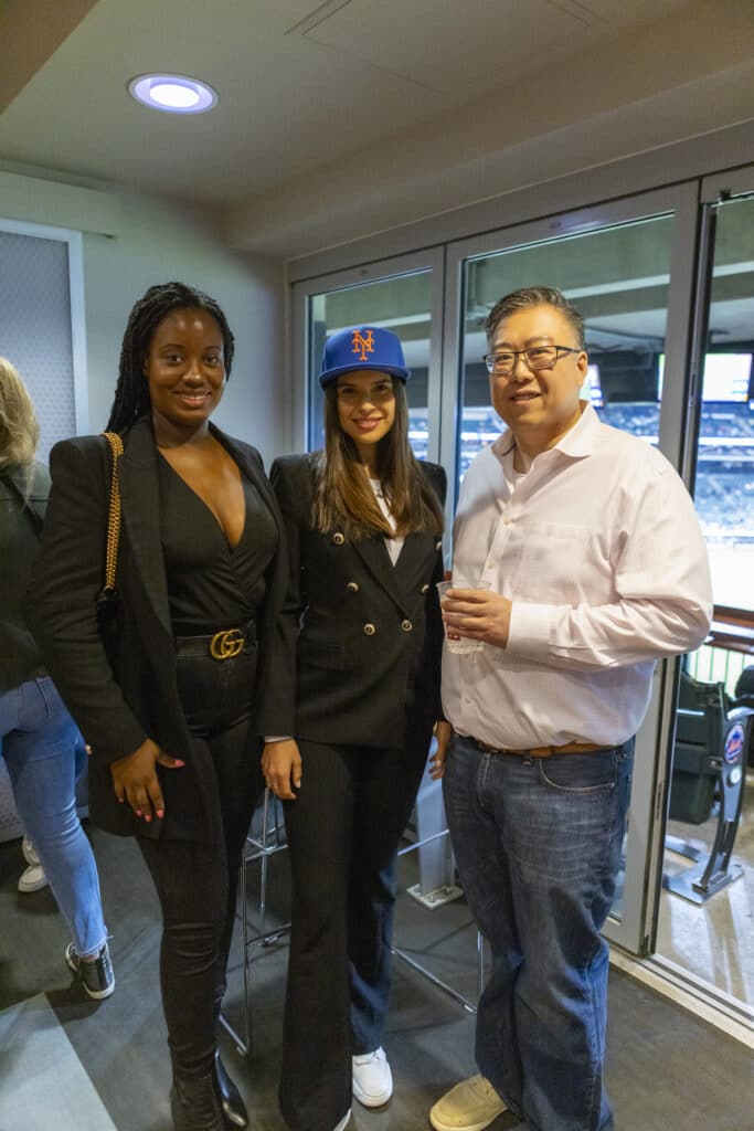 Three Chopra & Nocerino team members, including associate attorneys Michael Ma and Christine Duchatellier, posing for picture at NY Mets game where they threw the opening pitch