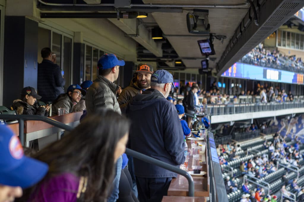 Team members of Chopra & Nocerino conversing in stands at New York Mets game