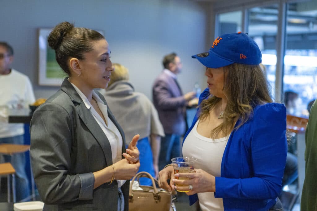 2 women of the Chopra & Nocerino team conversing at New York Mets game