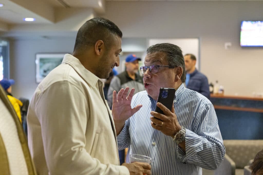 Sameer Chopra talking with team member at New York Mets game