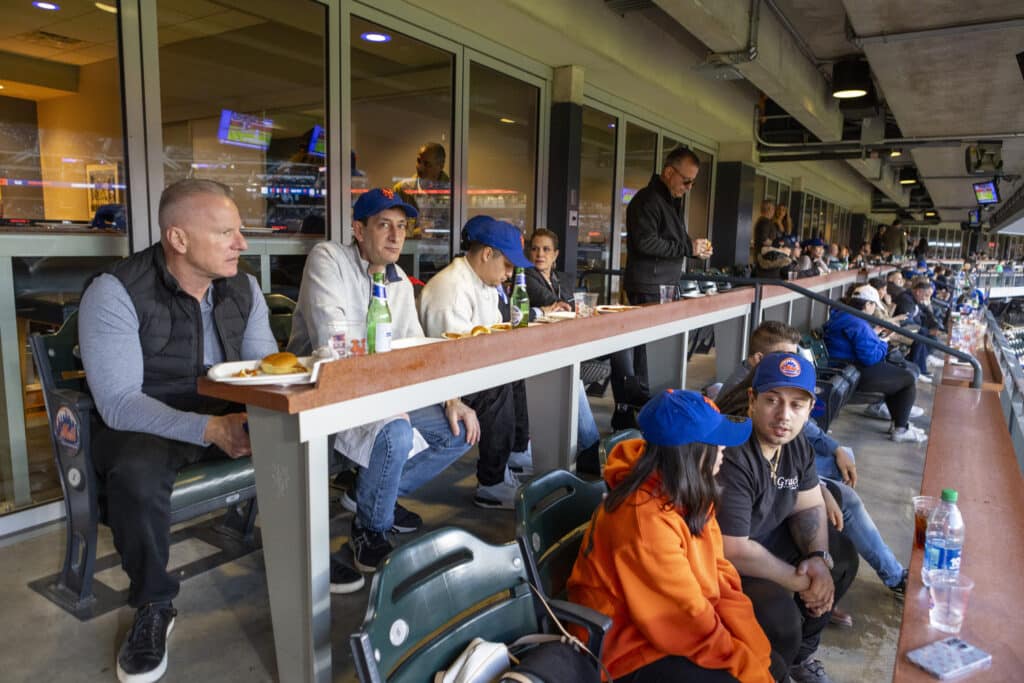 Team members of Chopra & Nocerino sitting in top of stands for New York Mets game