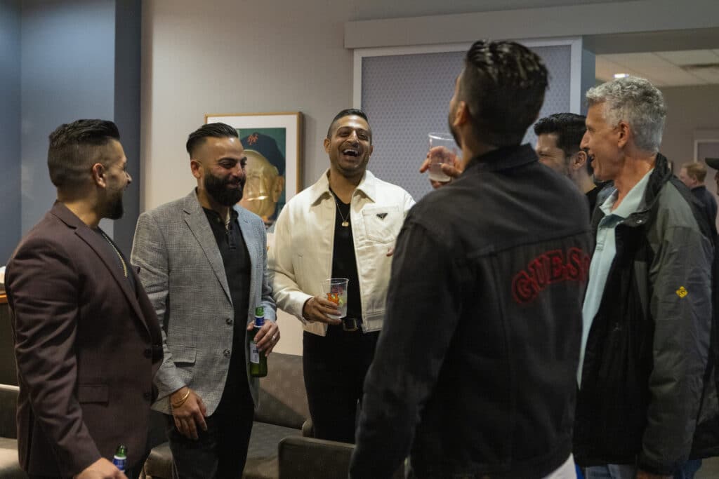 Sameer Chopra and other team members smiling and laughing at New York Mets game