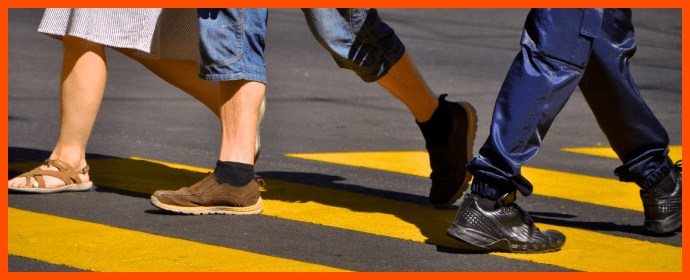 The image shows a close-up view of people crossing a pedestrian crosswalk